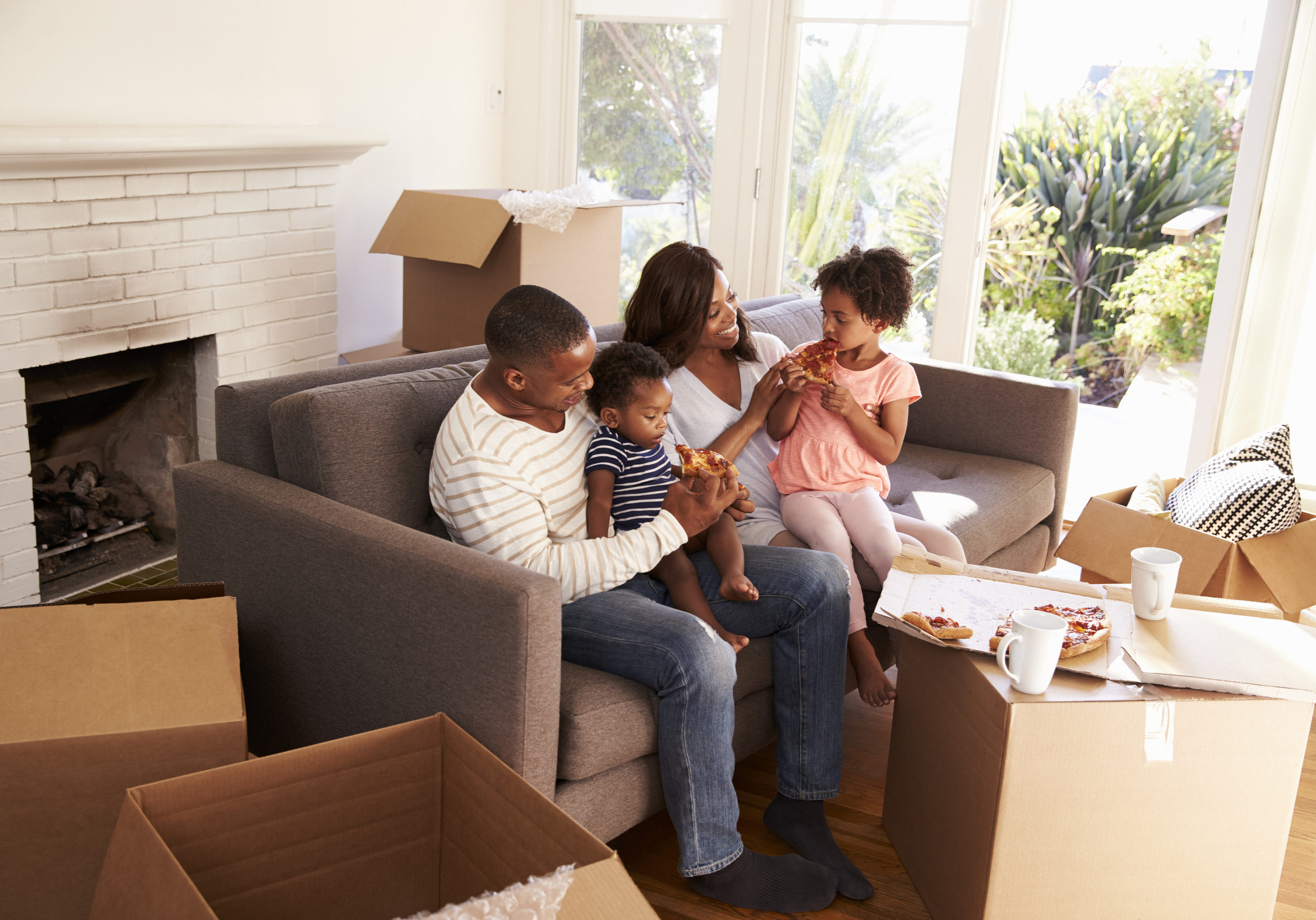 Family Take A Break On Sofa With Pizza On Moving Day